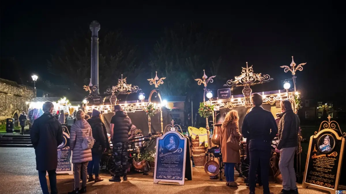 Visitors gathered at classic Christmas themed events featuring illuminated wooden stalls in a historic square
