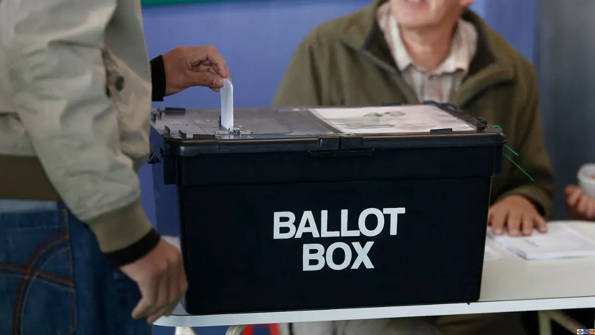 How to Register to Vote in UK guide showing a voter placing a ballot paper into an official ballot box at a polling station