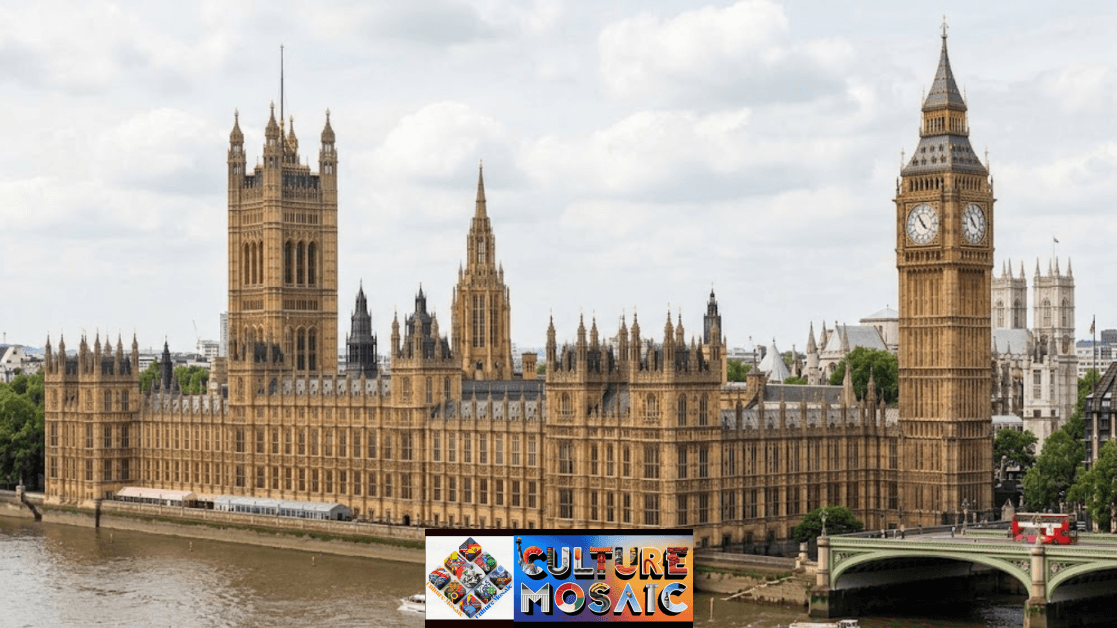 An elevated wide shot of the Palace of Westminster along the River Thames in London. The landmark features Victorian Gothic Revival architectural details, including ornate turrets, vertical window tracery, Victoria Tower on the left, and the iconic Elizabeth Tower (Big Ben) on the right. Westminster Bridge crosses the river in the lower right foreground.